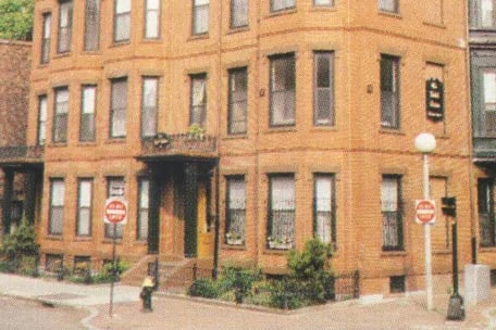 A red brick building with a black roof and a stop sign in front of it.