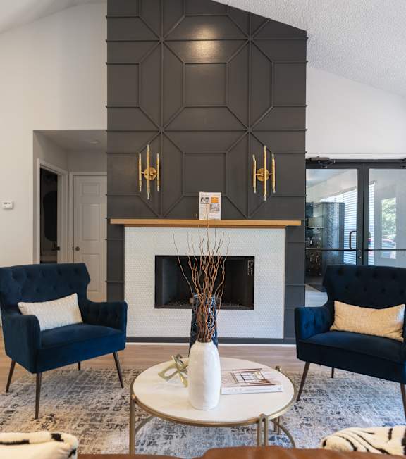 A living room with a fireplace and two chairs.