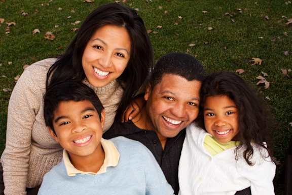 A family of four is sitting on the grass.