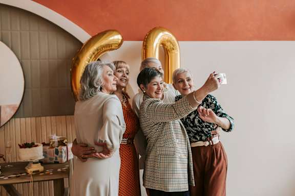 A group of people are taking a selfie with a number 2 balloon.