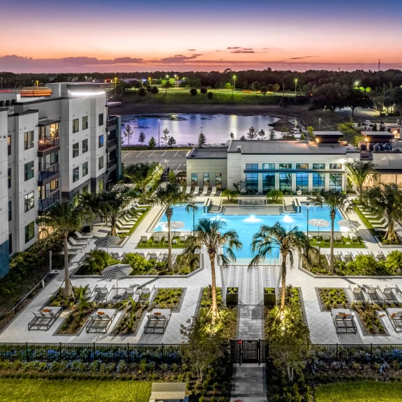an aerial view of a hotel and a swimming pool at dusk