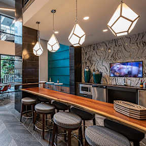 A modern bar area with a long wooden bar and stools.