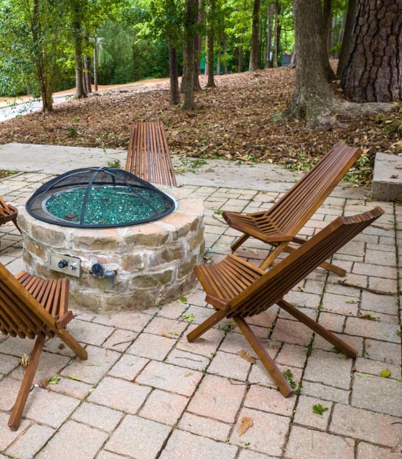 a stone fire pit with wooden chairs around it