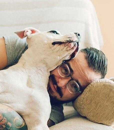 a man laying on a couch with a white dog