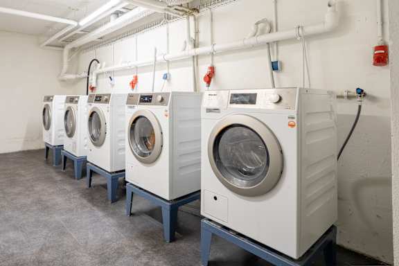 A row of industrial washing machines in a laundry facility.