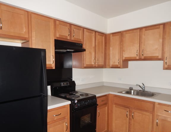 an empty kitchen with wooden cabinets and black appliances