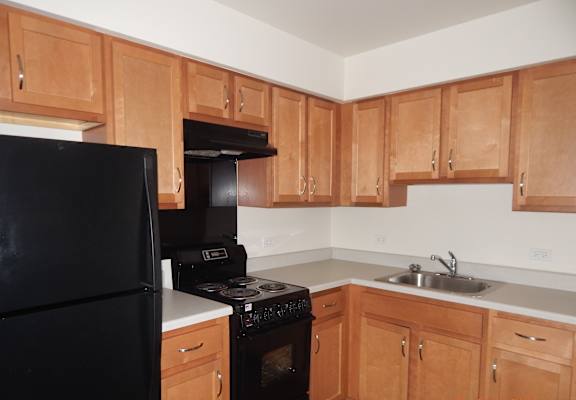an empty kitchen with wooden cabinets and black appliances