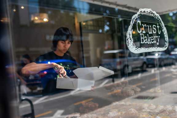 A person placing baked goods into a box inside a bakery. 