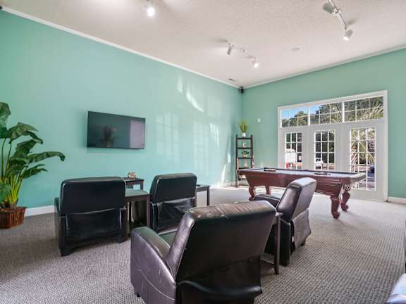 A room with a green wall and a pool table.