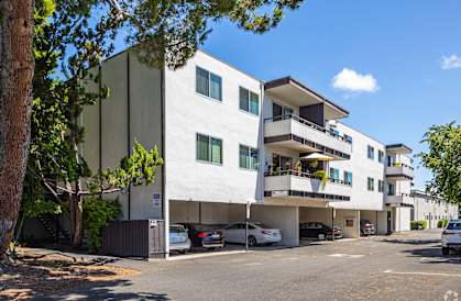 a white apartment building with cars parked in front of it
