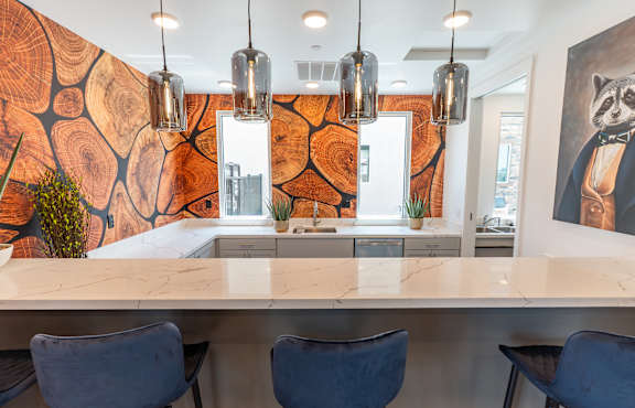 A kitchen with a marble countertop and blue chairs.