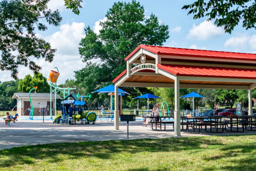 a pavilion with picnic tables and a playground in the background