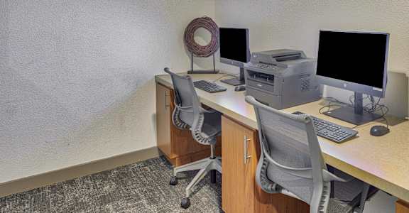 A computer desk with a monitor, keyboard, and printer.
