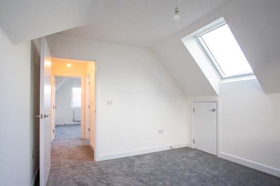 a bedroom with two skylights and a carpeted floor