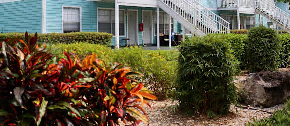 A blue house with a white balcony and stairs leading to the front door.