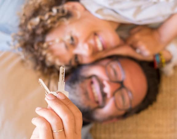 a man and a woman laying on a couch holding up a cigarette