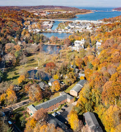 An aerial view of a town surrounded by trees with autumn foliage.