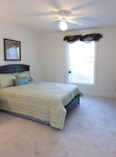 A bedroom with a bed, nightstand, and window.