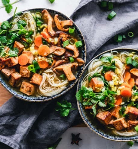 two bowls of pasta with tofu and vegetables on a table at Whitcomb Terrace Apartments, Merrillville