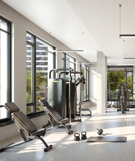 a gym with weights and cardio equipment in a building with large windows