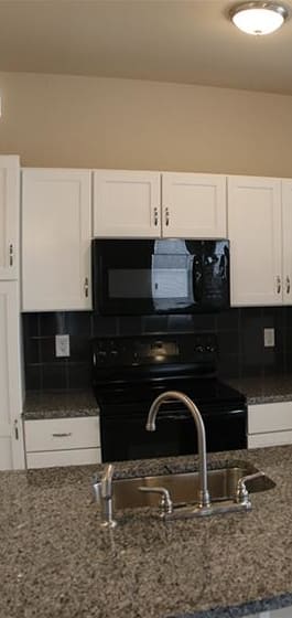 a kitchen with white cabinets and a black stove and refrigerator