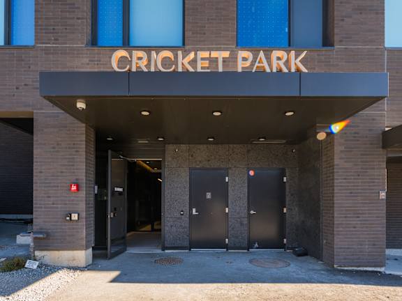 The front of a building with the words "Cricket Park" on it.