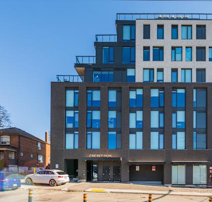 A modern building with a glass facade and a sign that reads "Cricket Park".