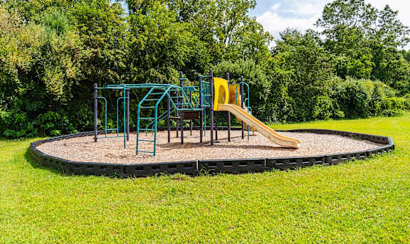 A playground with a slide and swings set in a grassy area at Coppermine Village Apartment, Bristol, CT, 06010