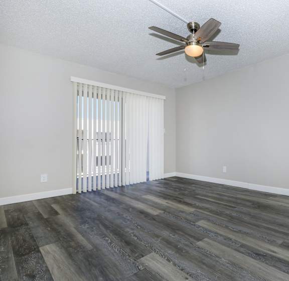 an empty living room with wood flooring and a ceiling fan