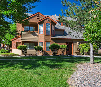 A house with a brown roof and a tree in front.