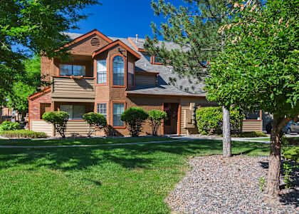 A house with a brown roof and a tree in front.