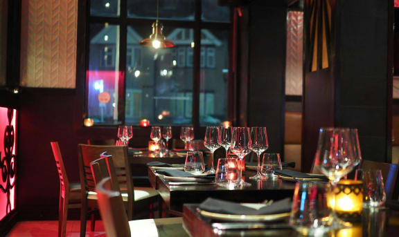 an empty restaurant table with wine glasses at night