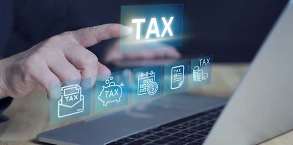 A person is interacting with a laptop that displays various tax-related icons.
