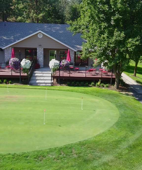 A golf course with a green and a white flag on it.