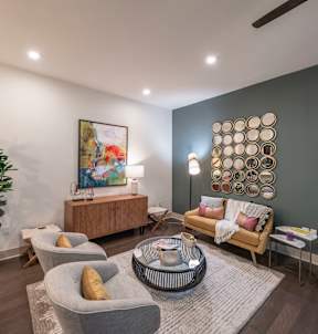 A living room with a grey sofa and a painting on the wall.