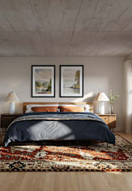 A bedroom with a large bed and a rug on the floor.