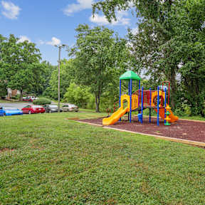 A playground with a yellow slide and a green roof.