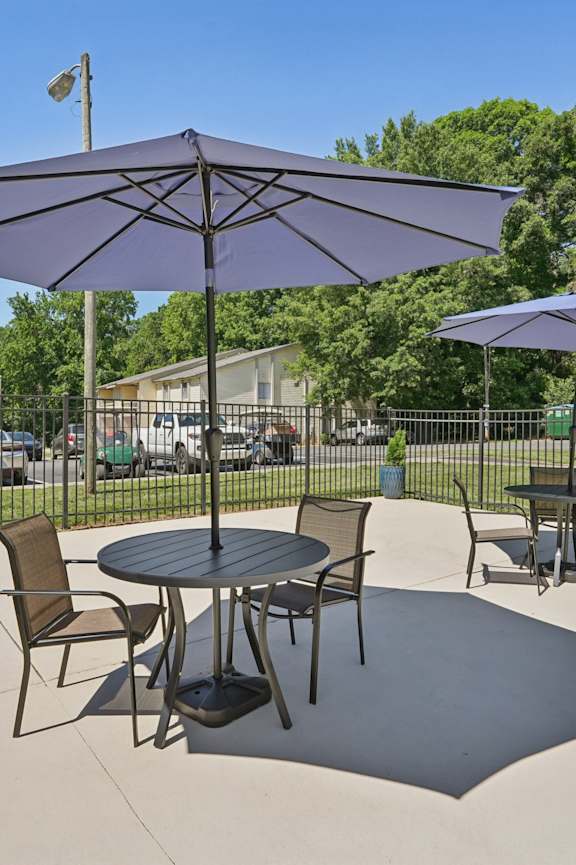 A patio with a table and chairs under an umbrella.