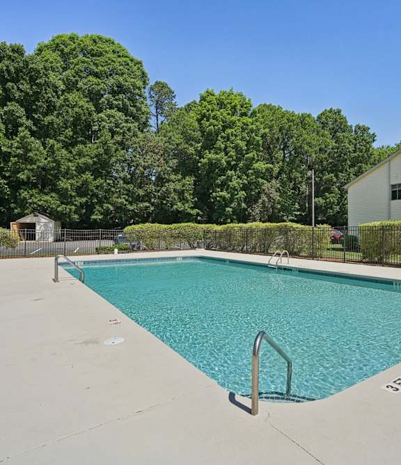 A small pool surrounded by a fence and trees.