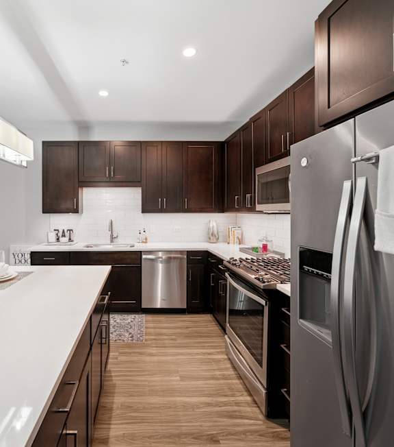 A modern kitchen with a stainless steel refrigerator and wooden flooring.