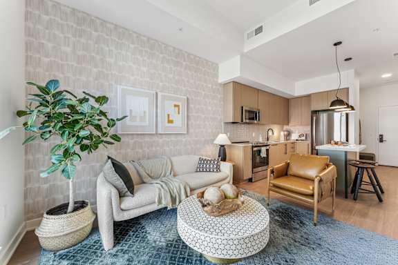 A living room with a white brick wall and a grey sofa.