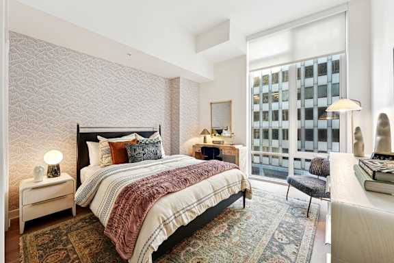 A bedroom with a large bed and a window overlooking a building.