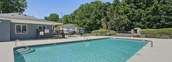 A swimming pool surrounded by trees and a house.