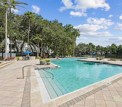 A large outdoor swimming pool surrounded by trees and a fountain.