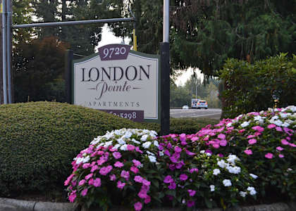 A sign for London Pointe Apartments is surrounded by flowers.