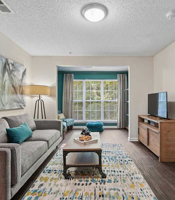 A living room with a grey couch and a painting on the wall.