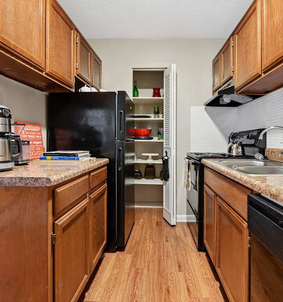 A kitchen with black appliances and wooden cabinets. at The Palms Apartments, Charleston, SC 29407