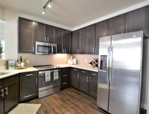 A modern kitchen with dark wood cabinets and stainless steel appliances.