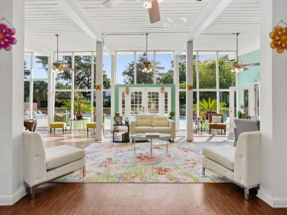 A white room with a floral rug and two white chairs. at The Palms Apartments, Charleston, SC 29407