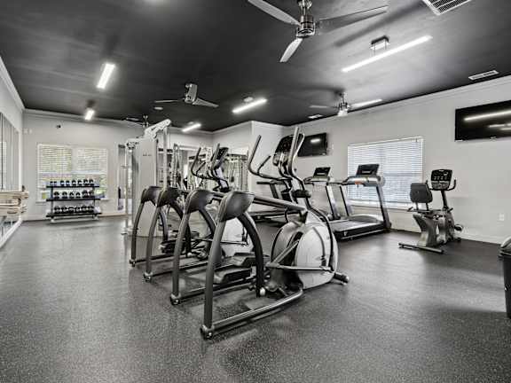A gym with a variety of equipment including treadmills, weights, and exercise machines.